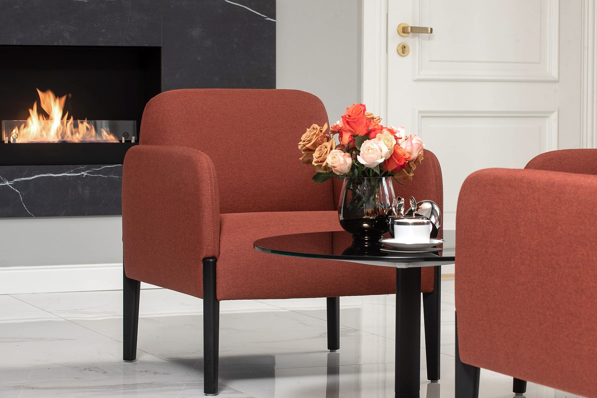 Waiting room with a fireplace and terracotta armchairs